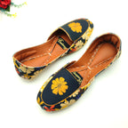 Floral patterned Khussa shoes worn by a female on a yellow background. 