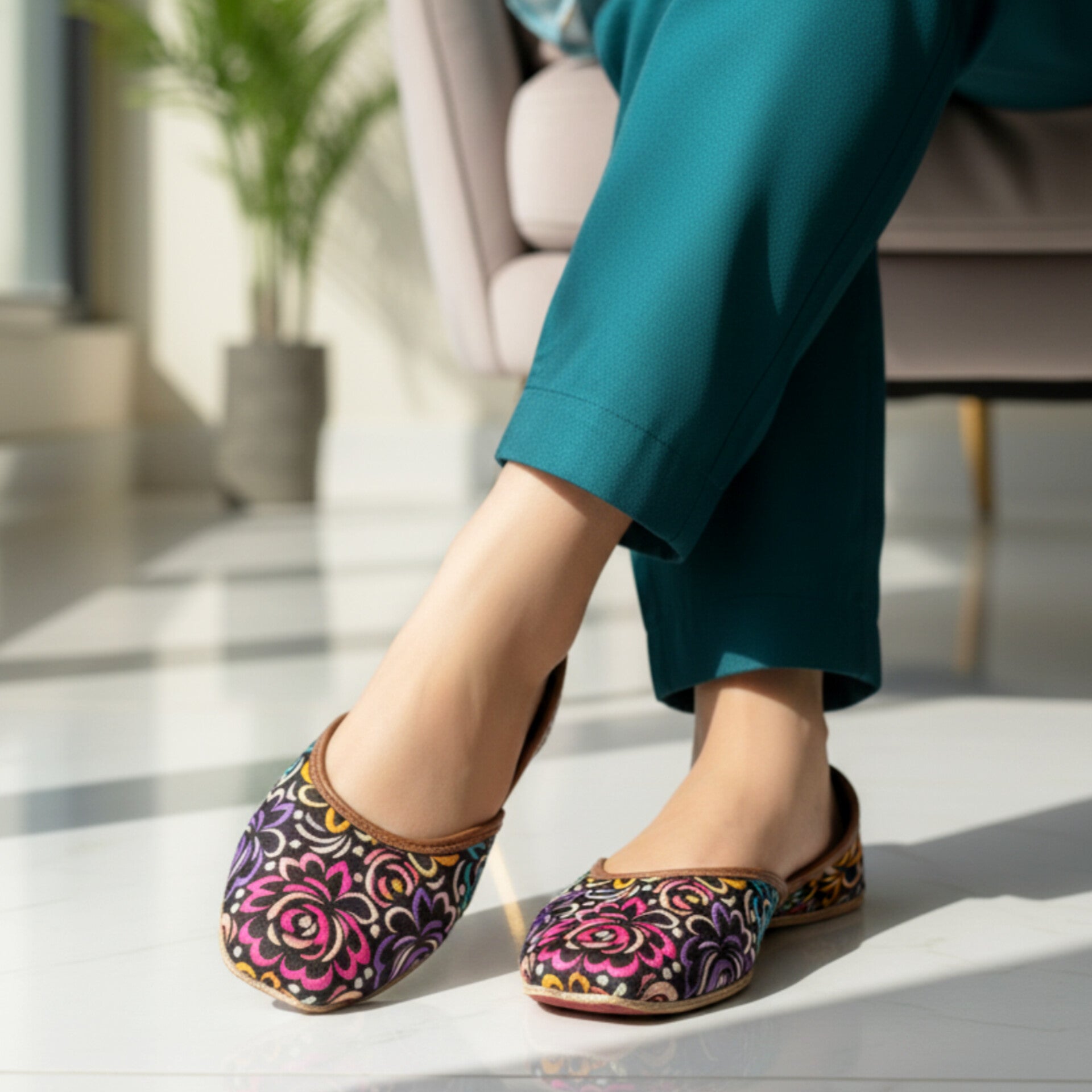 Woman wearing colorful floral-patterned Khussa on a light wooden floor.