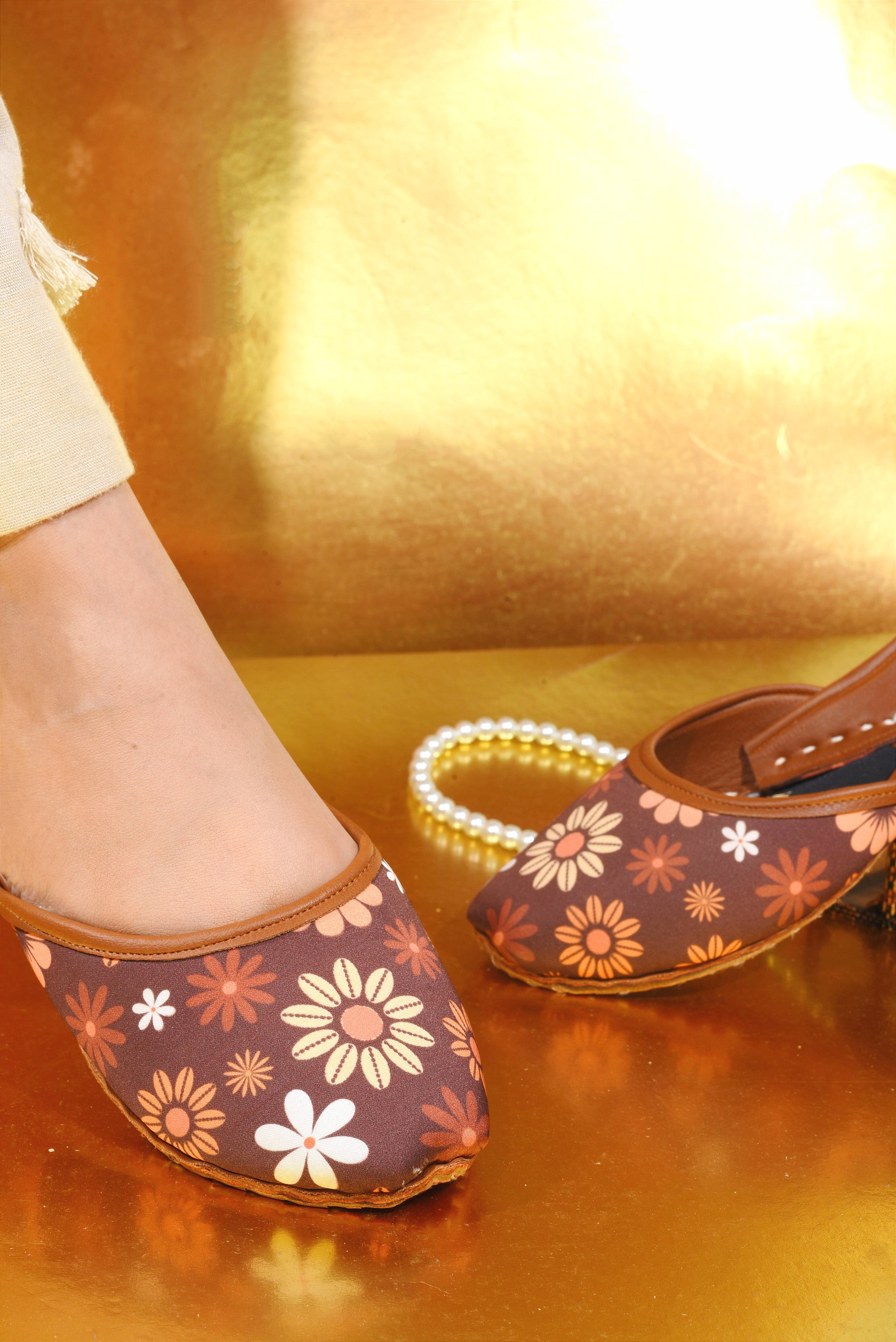 Brown floral-patterned Khussa shoes on a reflective gold surface
