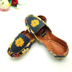 Floral patterned Khussa shoes worn by a female on a yellow background. 