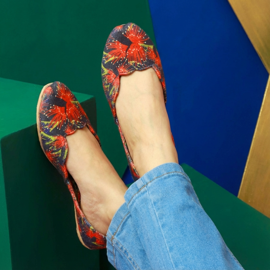 Colorful floral-patterned khussa shoes worn with blue jeans against a geometric background
